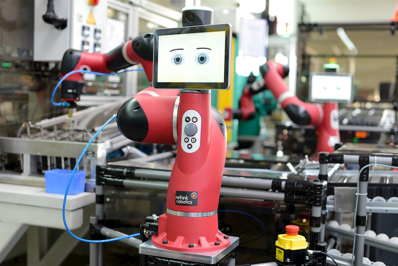 Cobot collaborativo rosso al lavoro in una linea manifatturiera con operatori e attrezzature