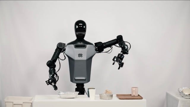 Robot umanoide davanti a un tavolo con oggetti da manipolare