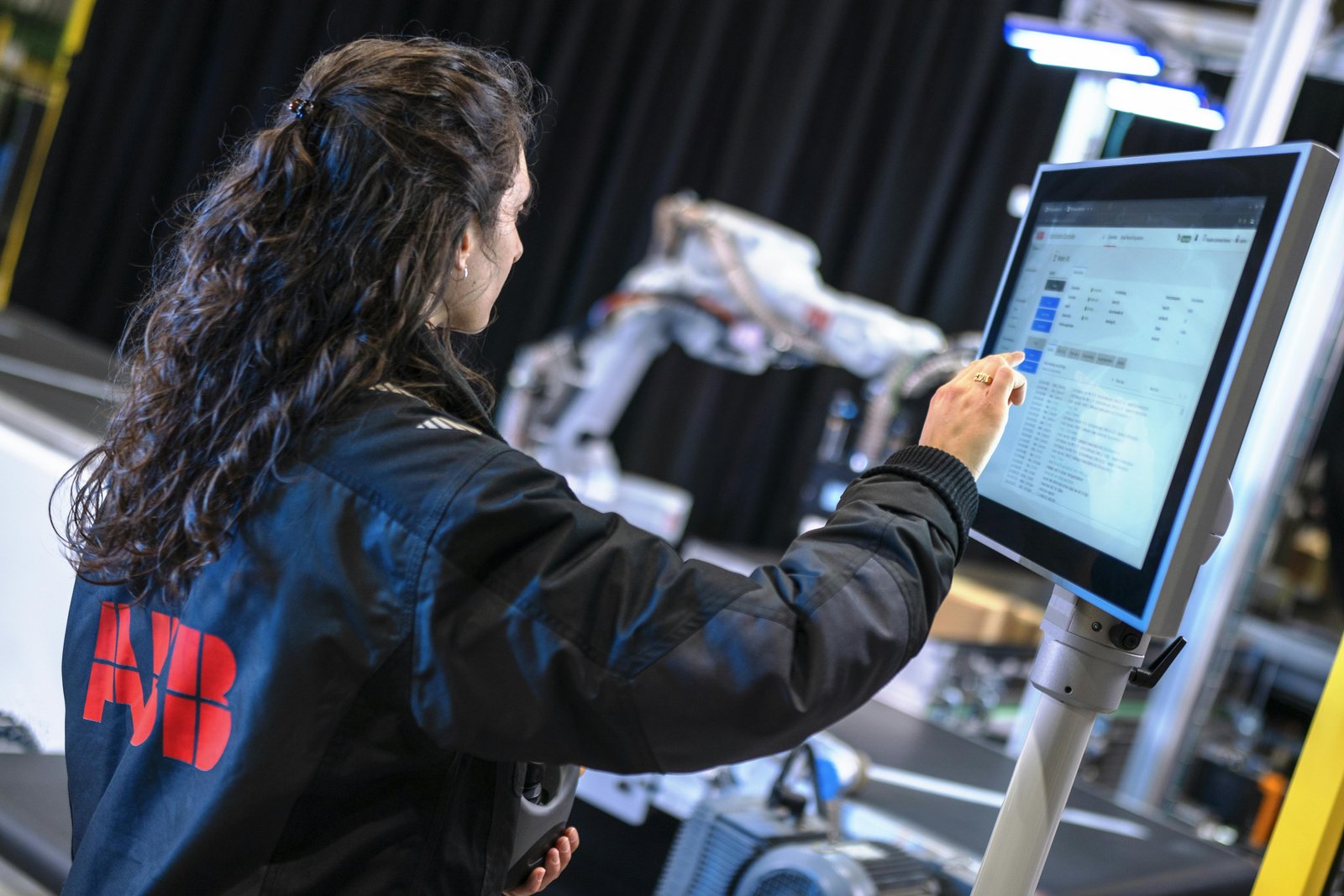 Tecnico davanti a pannello HMI con robot ABB sullo sfondo per verifica sicurezza e modalità operative