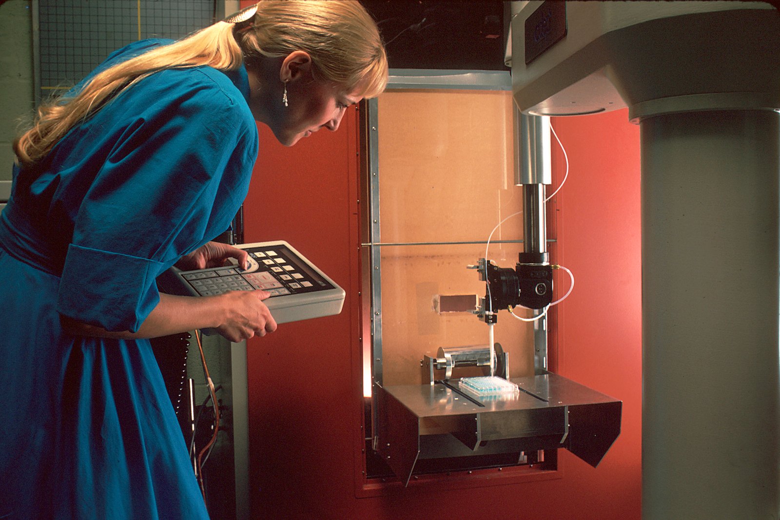 Tecnico in laboratorio con apparecchiatura robotica per handling di campioni genetici e diagnostici