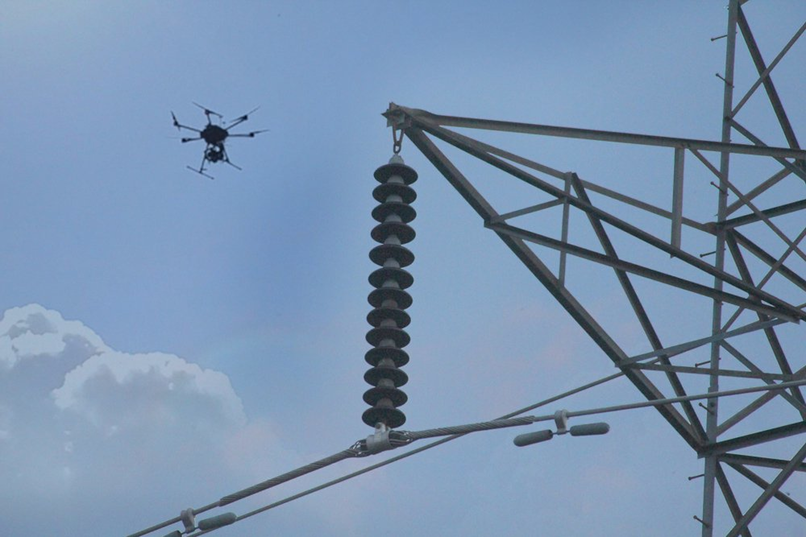Drone industriale vicino a un traliccio elettrico durante un'ispezione tecnica