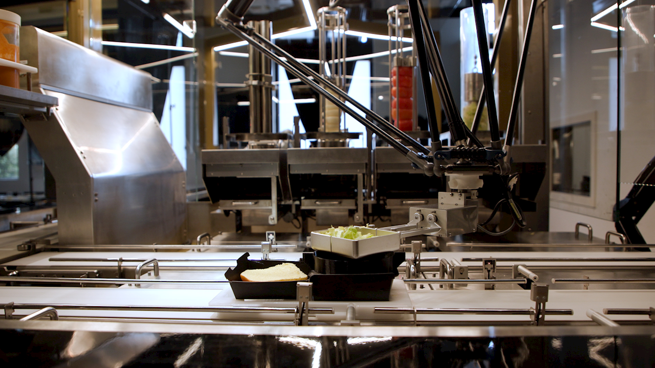 Robot delta BurgerBots che gestisce topping e assemblaggio rapido dei burger
