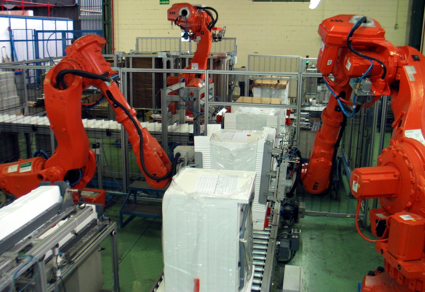 Robot industriali tradizionali in una cella di packaging con barriere di sicurezza