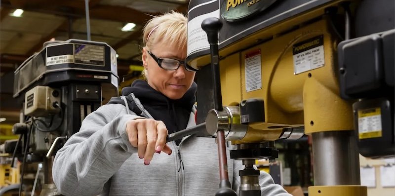Operatrice in officina utilizza una macchina utensile in ambiente manifatturiero