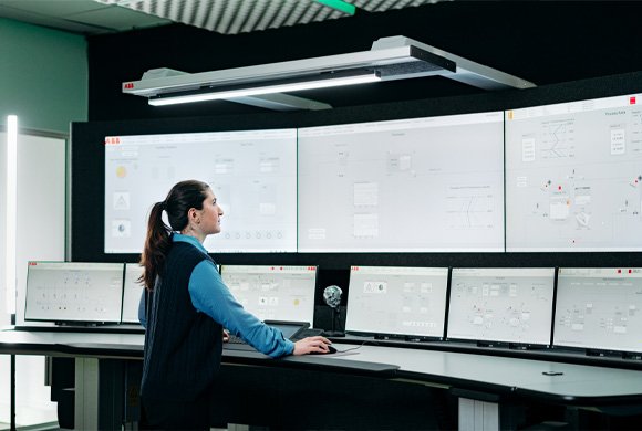 Operatrice in sala controllo ABB 800xA con dashboard di processo