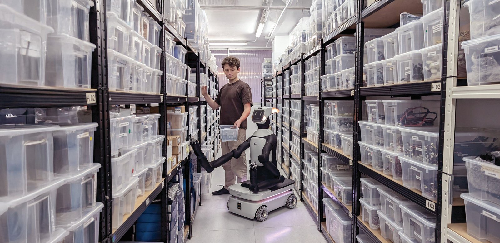 Robot mobile Tiago Pro di PAL Robotics in magazzino con scaffali e operatore