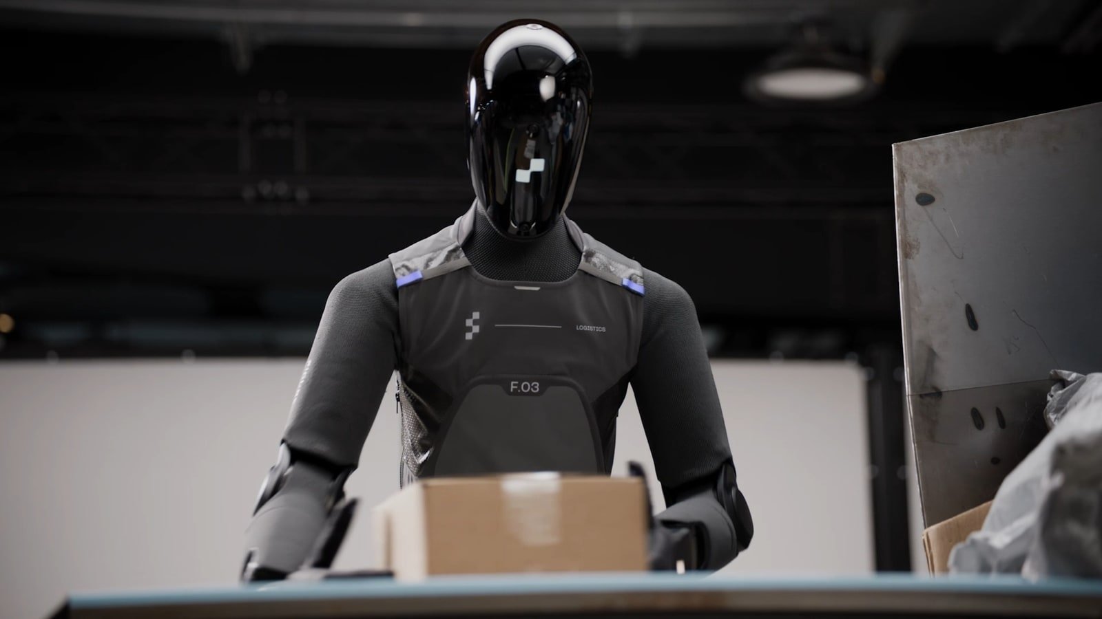 Fotogramma ufficiale Figure AI con Figure 03 che gestisce un pacco in un task logistico reale