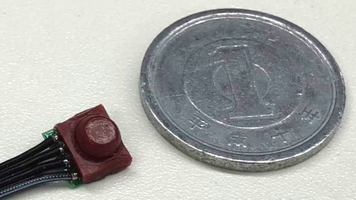 Sensore tattile miniaturizzato XELA vicino a una moneta per mostrare la scala