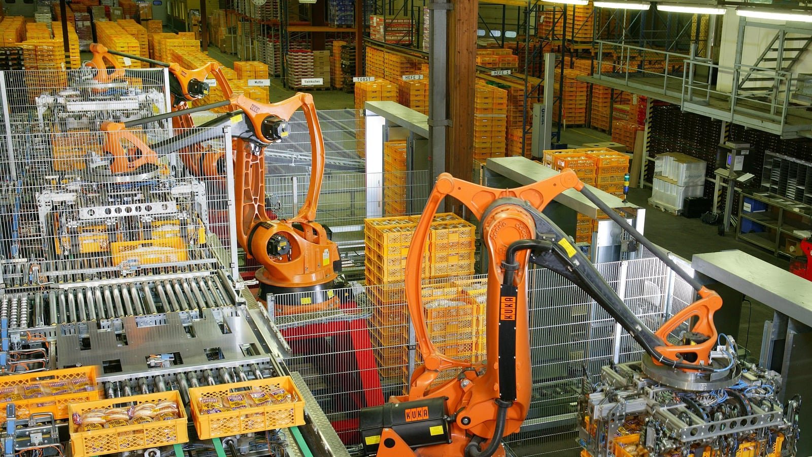Robot industriali arancioni che pallettizzano prodotti alimentari in una linea automatizzata